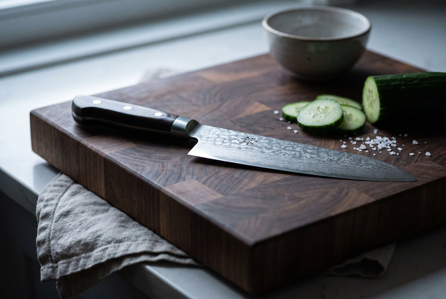 Damascus chef's knife resting on an end-grain cutting board